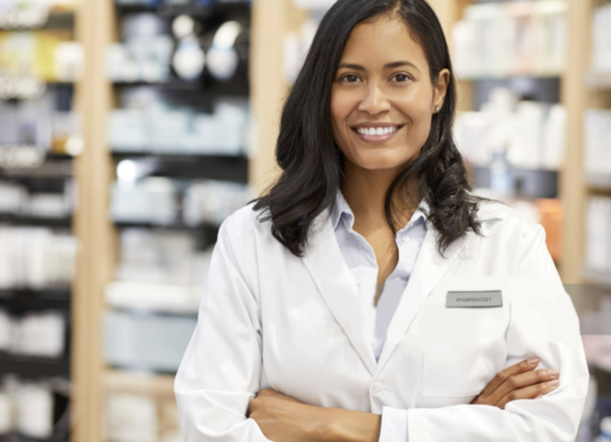 Pharmacist standing amongst the shelves looking at the camera